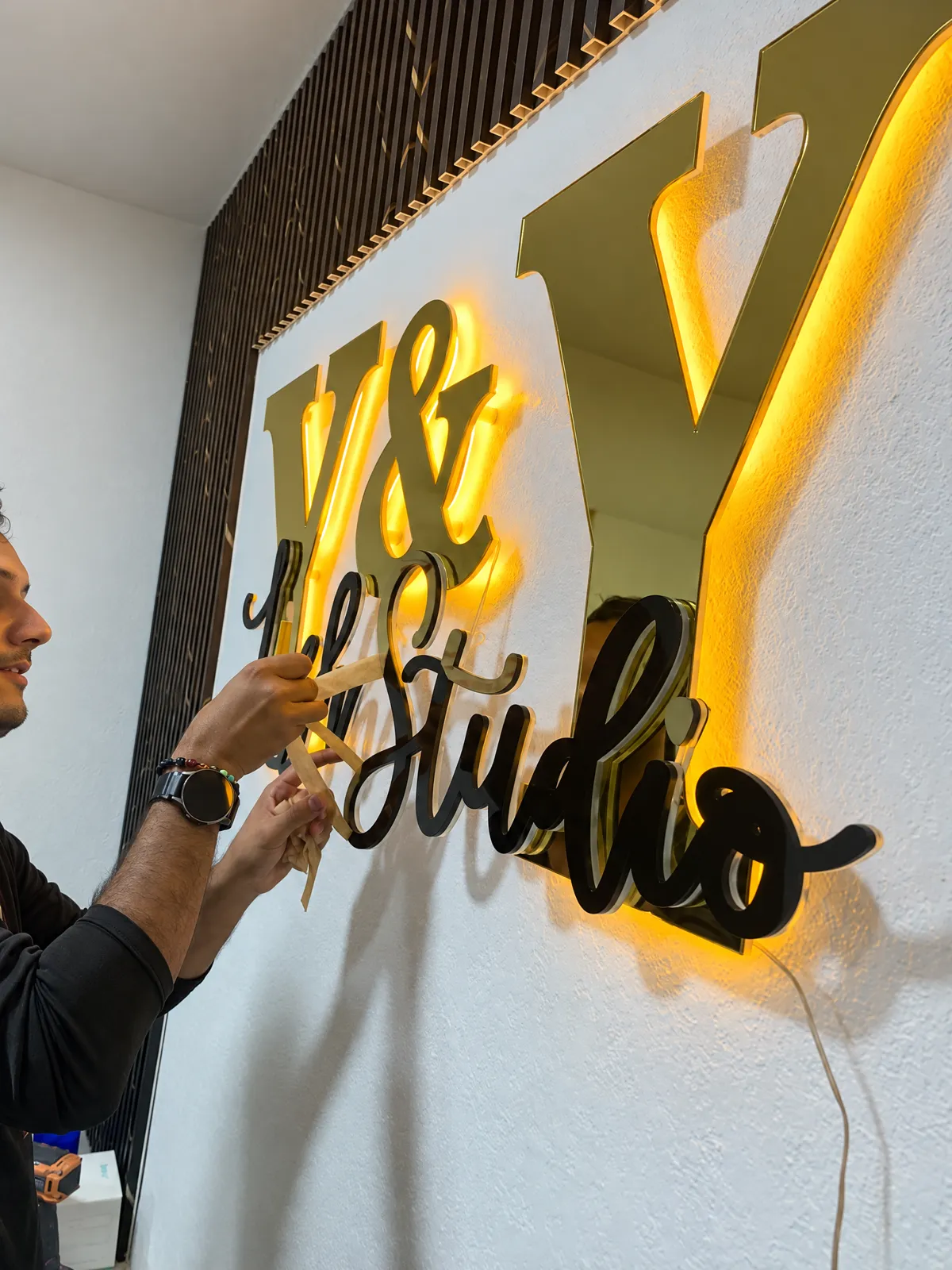Instalando letras doradas con luz trasera en un estudio de pestañas